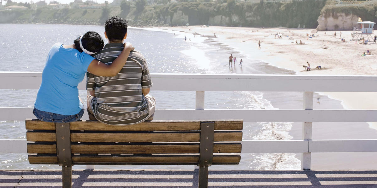 Couple sitting on a bench overlooking the ocean